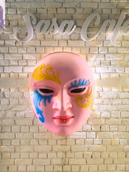 A close-up of the colorful mask that hangs on our wall. It's a unique piece of art that adds to the eclectic and vibrant personality of the cafe.