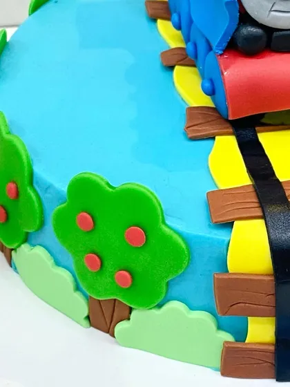 A close-up of the fondant details on the Thomas the Tank Engine cake, including the wooden tracks and apple trees.