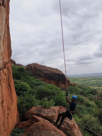 A climber descends a rock face, demonstrating controlled rappelling technique.