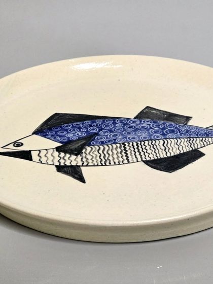 An angled shot of the sold geometric fish plate, highlighting its form and hand-painted details. Each piece is crafted to be a unique home decor accent.