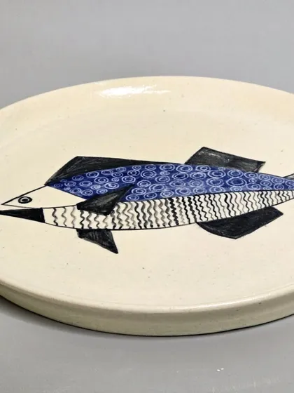 An angled shot of the sold geometric fish plate, highlighting its form and hand-painted details. Each piece is crafted to be a unique home decor accent.