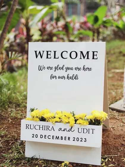 A simple and elegant welcome sign for a Haldi ceremony. I believe that even the smallest details, like this personalized sign with fresh flowers, contribute to a warm and welcoming guest experience.