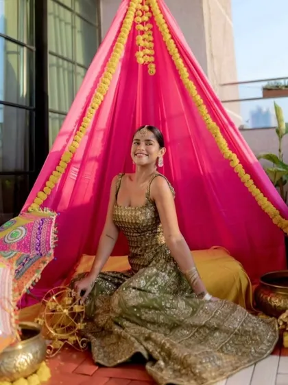 A cozy canopy tent seating area I created for a Mehendi party. The bright pink fabric and marigold details provide a fun, traditional space for guests to relax.