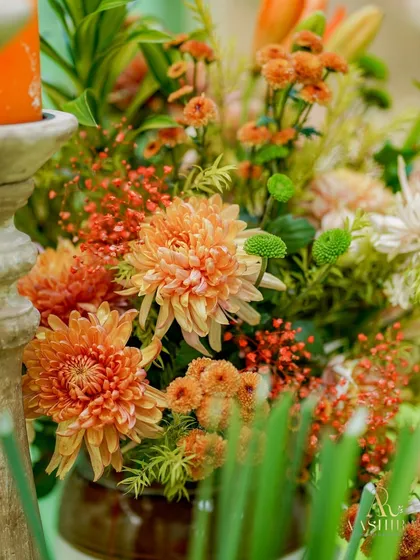 A close-up of a floral arrangement featuring burnt-orange chrysanthemums, creating a warm and textured look.