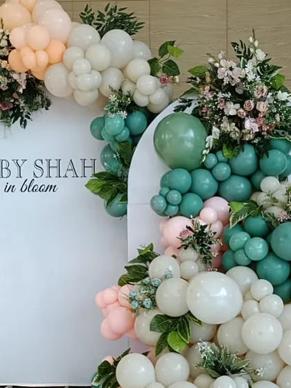 A fresh take on the "Baby Shah in Bloom" theme, using a mix of sage green, peach, and white balloons with beautiful floral arrangements for a sophisticated feel.