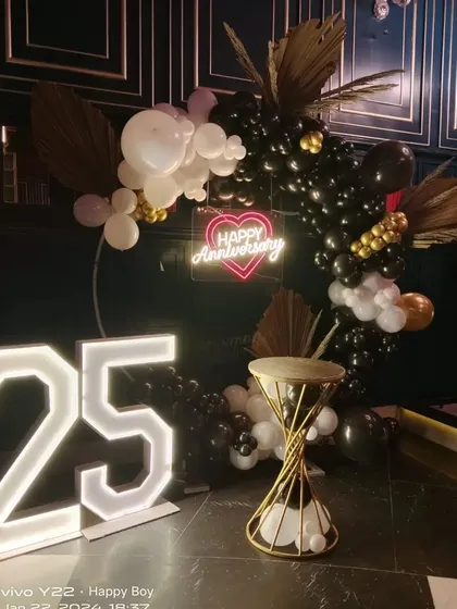 A full view of the 25th anniversary setup, highlighting the placement of the light-up numbers, the balloon arch, and the decorative stand.
