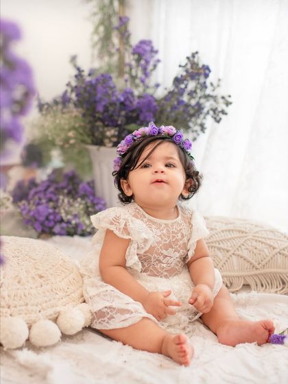 A close-up of the birthday girl in her purple floral crown, looking curious and cute during her first birthday photoshoot.