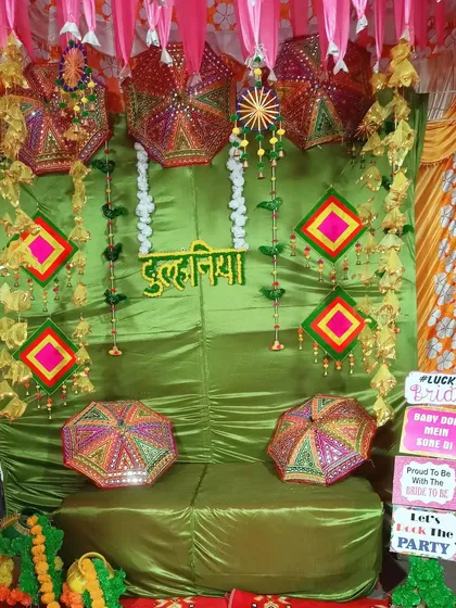 Another view of the green-themed Mehndi decor, this time with a 'Dulhaniya' sign. The Rajasthani umbrellas and quirky props add a playful touch to the celebration.