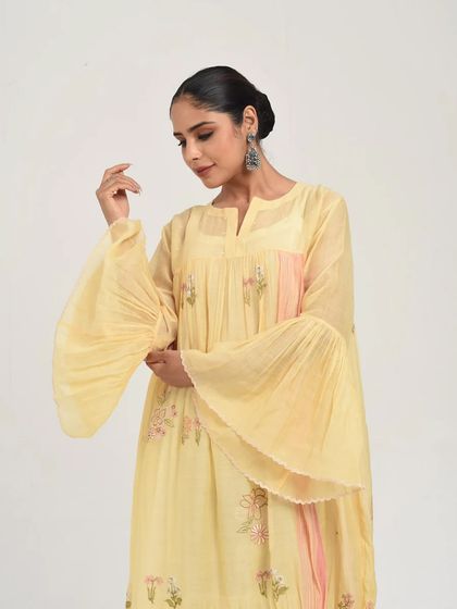 A model showcases a pastel yellow dress with dramatic flared sleeves, a perfect blend of comfort and high fashion.
