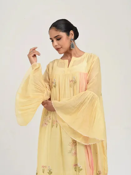 A beautiful pastel yellow anarkali with dramatic pleated bell sleeves and subtle floral embroidery, a perfect blend of modern trends and classic charm.