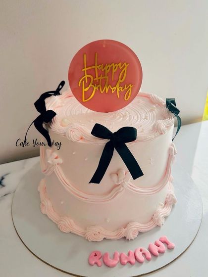 A trending vintage cake in pink and black, with delicate piping and bows.
