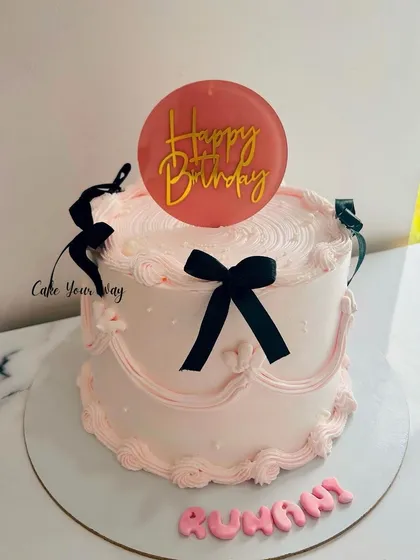 A trending vintage cake in pink and black, with delicate piping and bows.