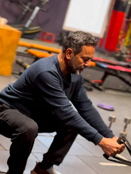 This client is performing a squat while using a resistance tool, which adds a unique challenge to the movement. This helps improve his form and engage his muscles in a different way.
