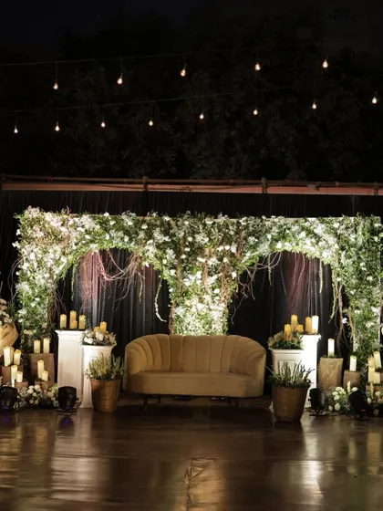 For a more intimate and rustic feel, we designed this beautiful stage setup. The combination of a lush green floral arch, warm candlelight, and natural wood elements created a deeply romantic and earthy setting for the couple.
