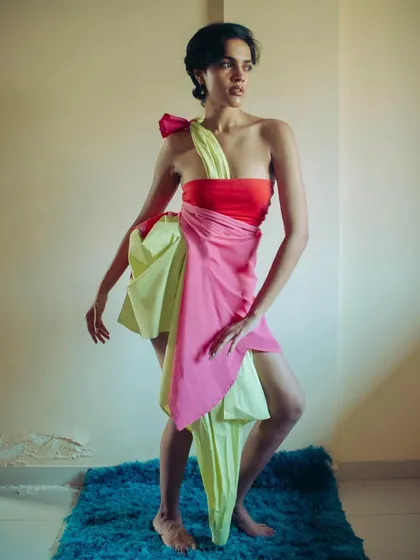 An experimental styling shot where two shirts are draped to create a dress. The image captures a moment of creative improvisation and movement in a simple, intimate setting.
