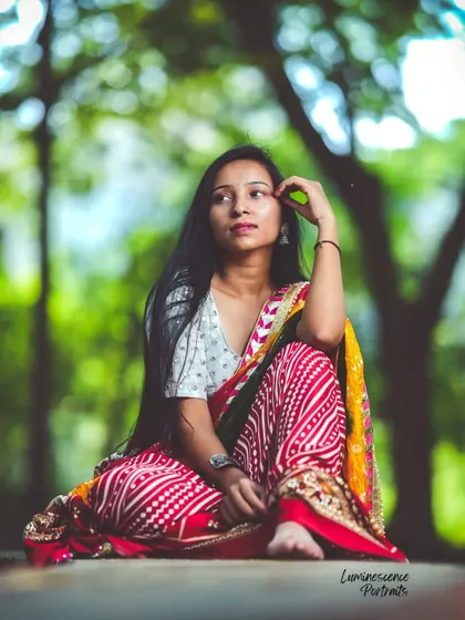 A beautiful seated portrait in a natural setting, capturing a thoughtful expression and the vibrant details of the traditional attire.