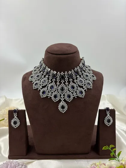 A statement AD necklace with a dense, layered design in blue and white stones.