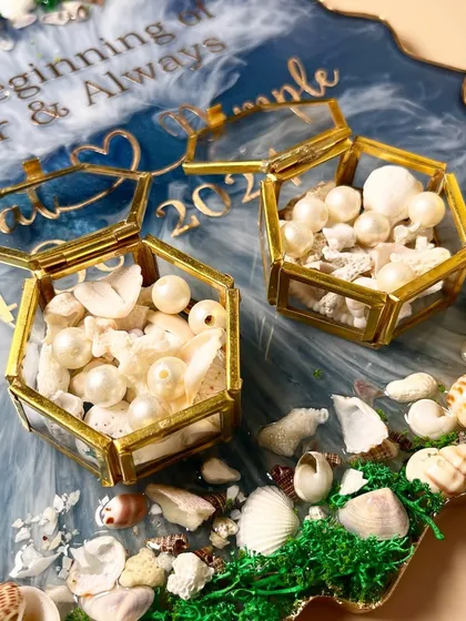 A detailed view of the ring boxes and the beautiful texture created by the shells and moss on the platter's edge.