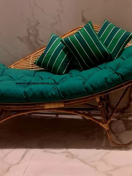 A full view of our rattan chaise lounge with plush green cushions. Its sleek, flowing lines and natural material bring a sense of resort-style luxury and relaxation to your home.