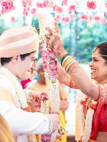 The joyful exchange of garlands during a cross-cultural wedding, a moment filled with laughter and happiness. I ensure that traditional rituals are celebrated beautifully, blending cultures seamlessly.