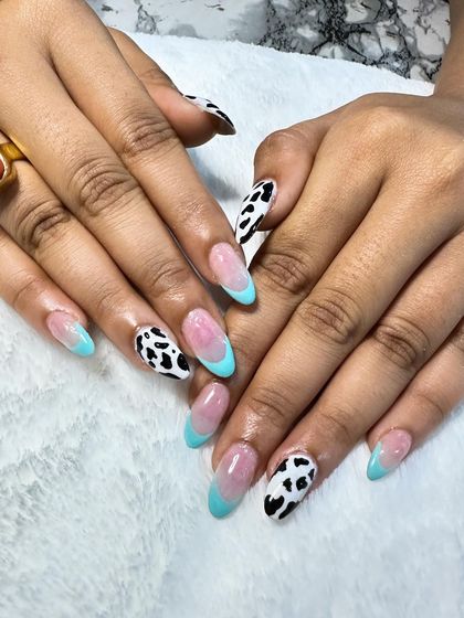 A playful and trendy set combining light blue French tips with bold cow print accent nails. It's a great way to mix classic and fun styles.