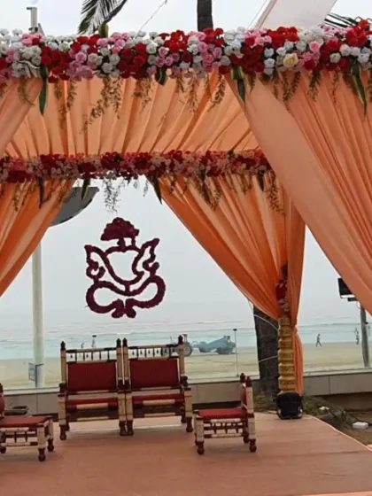 This peach-themed mandap combines traditional elegance with a soft, modern color palette. A floral Ganesh design hangs in the center, adding a sacred touch to the beachside ceremony.