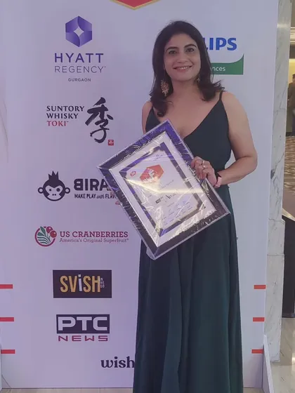 This is a photo of me at the awards night, holding my certificate against the backdrop of event sponsors like Hyatt Regency and PTC News. It was a proud moment for my home bakery.
