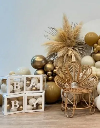 Details matter, like these transparent 'BABY' boxes filled with small balloons and a miniature rattan peacock chair, adding a touch of boho charm.