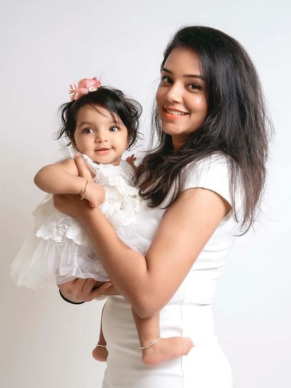 A beautiful mother holding her little fairy. The simple white outfits and clean background keep the focus on their sweet connection.