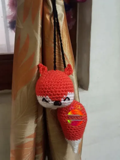 A clever and cute fox curtain tie-back. The design includes the fox's head and a separate bushy tail, making it look like the fox is hugging the curtain.