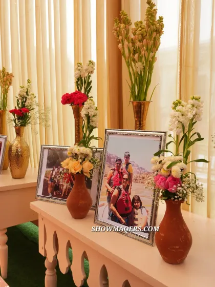 A personalized corner displaying family photos amidst beautiful floral arrangements in terracotta and brass vases.
