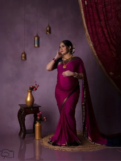 A thoughtful and elegant pose. The rich purple and red tones of the background and her saree create a royal and sophisticated look.