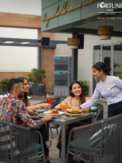 Our staff is dedicated to making your experience seamless. Here, a guest is served with a smile at our rooftop restaurant, ensuring every detail of your meal is perfect.