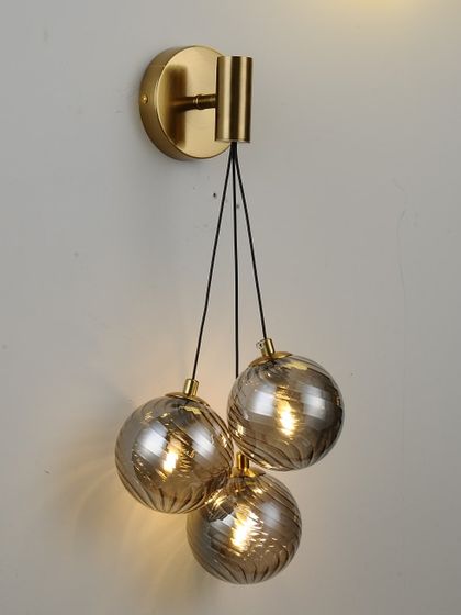 A wall-mounted cluster of three smoked glass globes. This fixture provides a beautiful cascade of light in a compact form.