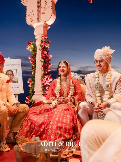 A happy, candid portrait of the couple seated during their wedding ceremony, sharing a laugh.