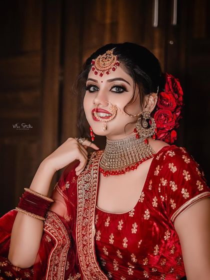 A classic beauty shot of the bride in her red velvet lehenga. Her pose is elegant, and she looks directly at the camera with a confident and alluring expression. (Duplicate of 105)
