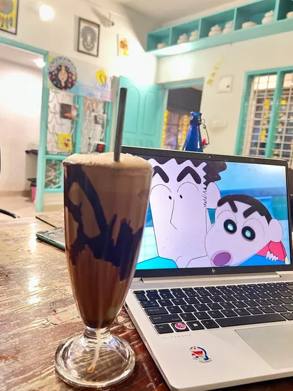 The perfect setup for a relaxing afternoon. A tall glass of our rich chocolate shake next to a laptop playing a favorite cartoon. It's your cozy home away from home.