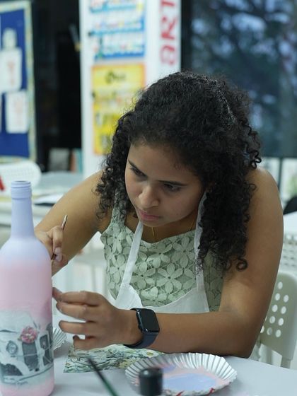 A participant carefully applies a design to a bottle in a decoupage workshop. This craft is all about precision and patience, with beautiful results.