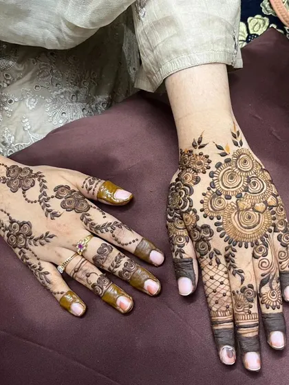 This shows two different styles side-by-side. One hand has a simple, delicate floral vine, while the other features a more complex Indo-Arabic design, showing the range of floral art.