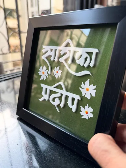 A side view of the 'Sarika Pradip' tabletop nameplate, showing its sturdy frame and the clarity of the glass cover.