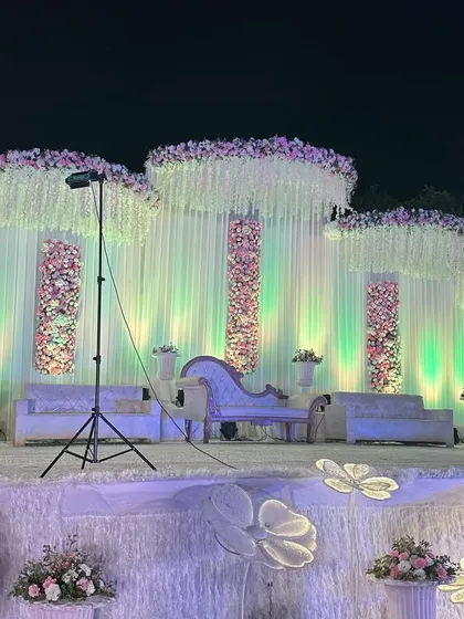 Another angle of the elegant white wedding stage, showing the full width and the careful placement of the illuminated floral floor lamps that add a whimsical touch.