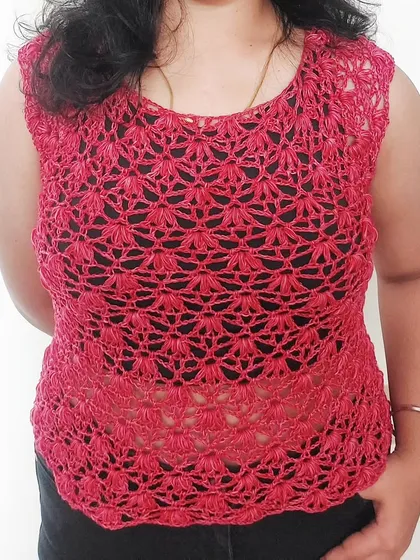 This is the Rinnina Top, a beautiful sleeveless piece made with an intricate, lace-like stitch. It's perfect for dressing up or down during the warmer months.