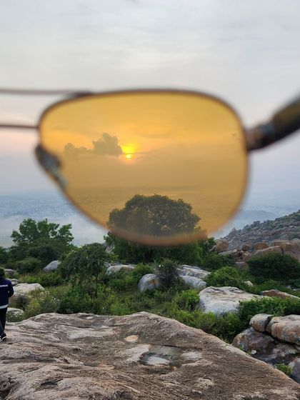 A creative shot capturing the sunrise at Makalidurga through the lens of a pair of sunglasses.