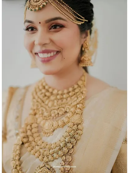A detailed close-up of the bride's face, showcasing her flawless makeup and the intricate design of her gold necklace.