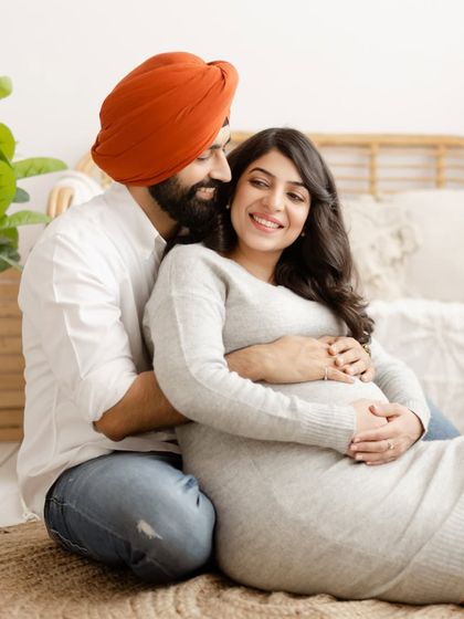 A cozy and intimate portrait of an expecting couple in our boho-themed studio. The warm smiles and gentle embrace perfectly capture the excitement of their journey.