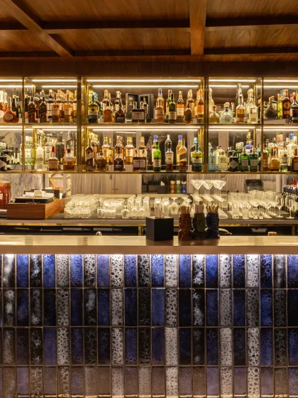 Our fully stocked indoor bar, with its beautiful blue-tiled front and warm backlighting. It’s an inviting space to start or end your evening.