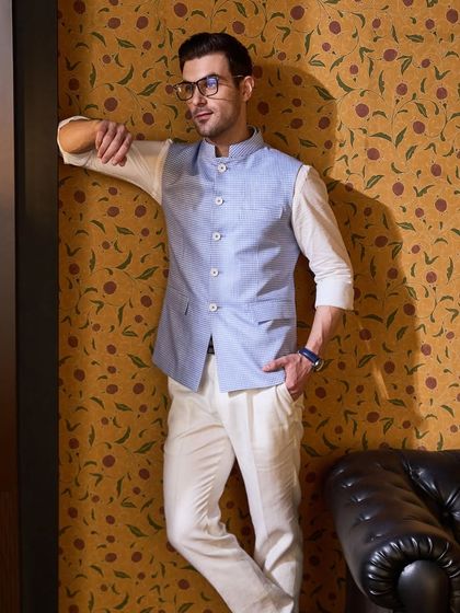 A pastel blue waistcoat paired with a crisp white linen shirt and chinos. This is a perfect, breezy look for a guest at a summer evening party or a beach wedding.