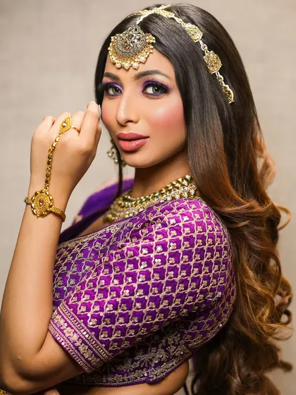 A side profile of the purple glam look, showing the beautiful hairstyle and the way the makeup complements the gold jewelry.