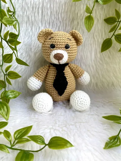 A classic teddy bear, a timeless gift for any age. This one is shown with a red ribbon, a black tie for 'Daddy Bear', and with expressive green eyes. They are soft, cuddly, and made to be loved.