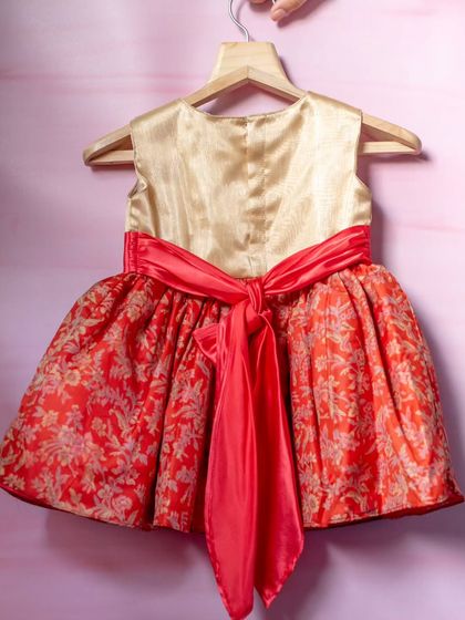 A vibrant dress in red and gold brocade. The rich fabric and festive colors make this a perfect choice for holiday celebrations or cultural events, finished with a bright coral sash.